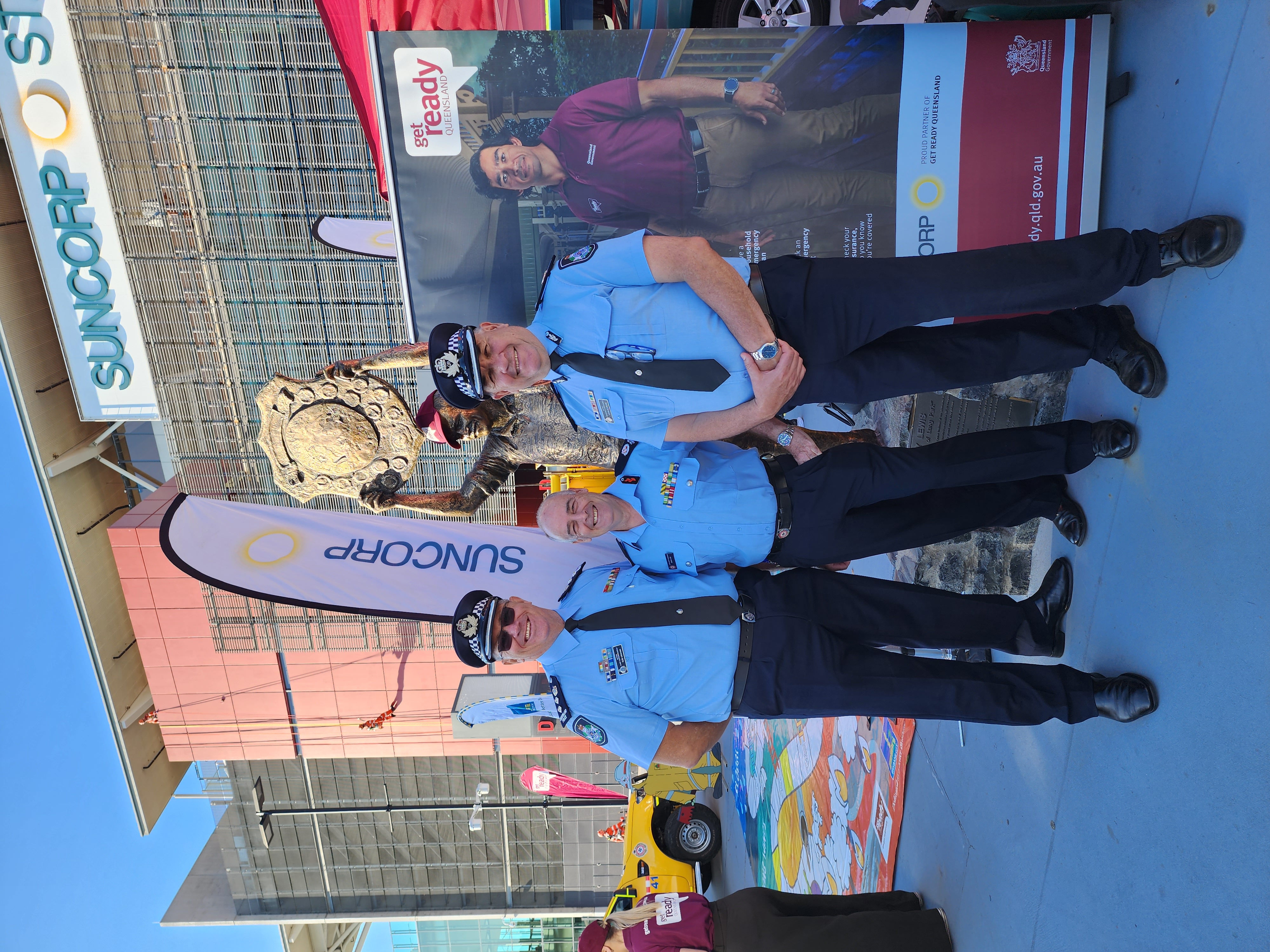 emergency services workers standing in front of wally lewis statue